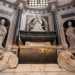 Alle sue spalle, non meno imponente, ammiriamo il monumento sepolcrale di Bona Sforza, realizzato a Napoli fra il 1589 e il 1595, innalzato in memoria della duchessa di Bari di cui ospita le spoglie. La Sforza  qui rappresentata da una statua di marmo bianco immacolato mentre  in ginocchio e con le mani giunte in atto di preghiera. Su di lei vegliano San Stanislao e San Nicola